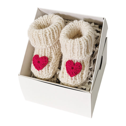 Rankų darbo balti vilnos tapukai kūdikiui su raudona širdele dovanų dėžutėje. Palankynų ir baby-shower dovana.